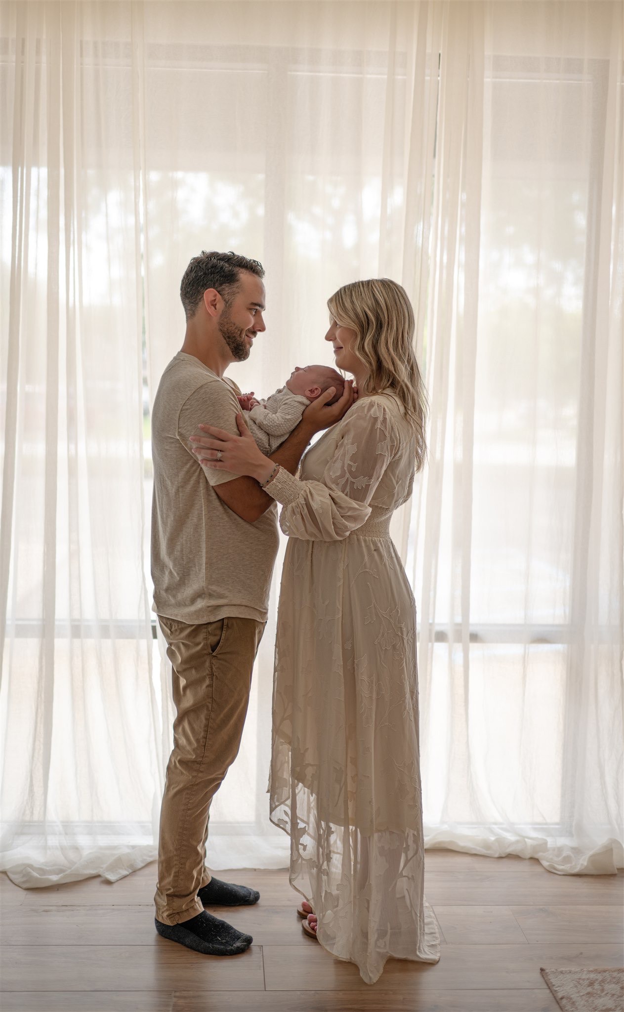 grand rapids newborn photography parents holding newborn window light