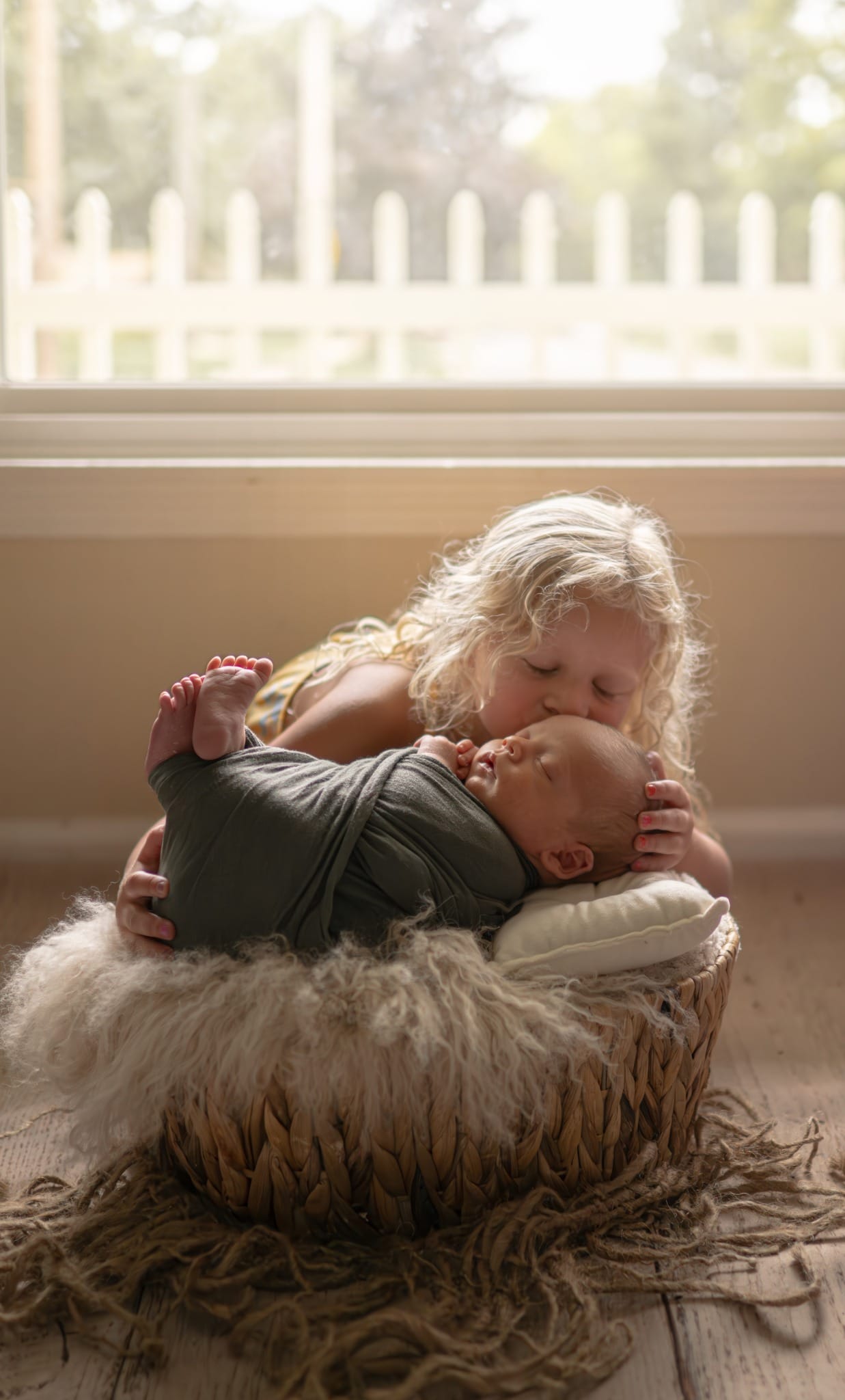 grand rapids newborn sibling kissing baby basket